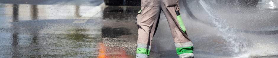Worker and cistern truck washes and disinfects the asphalt. Cleaning and disinfects the streets with water truck.